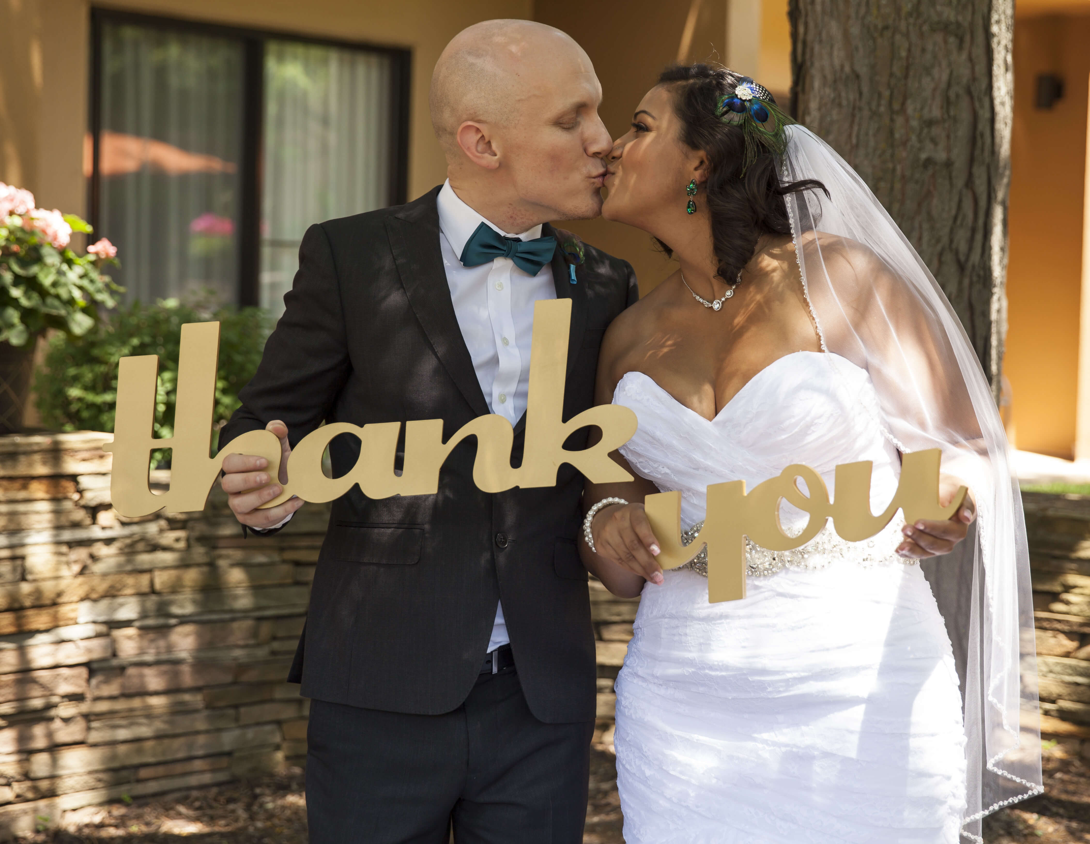 bride and groom kissing and holding a golden die cut "thank you" sign