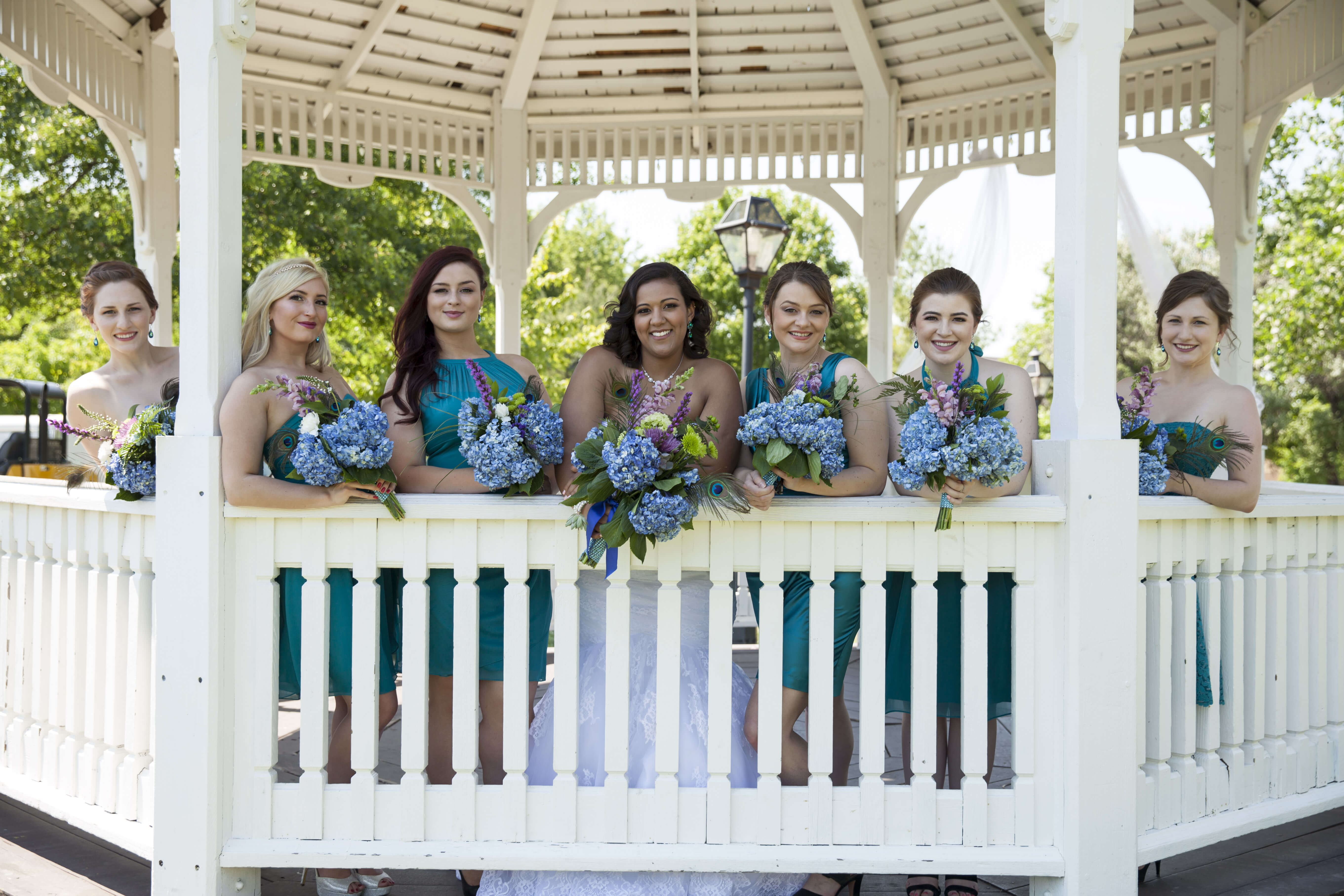 the bride and her bride's maid holding their blue flower bouquets under the gazebo
