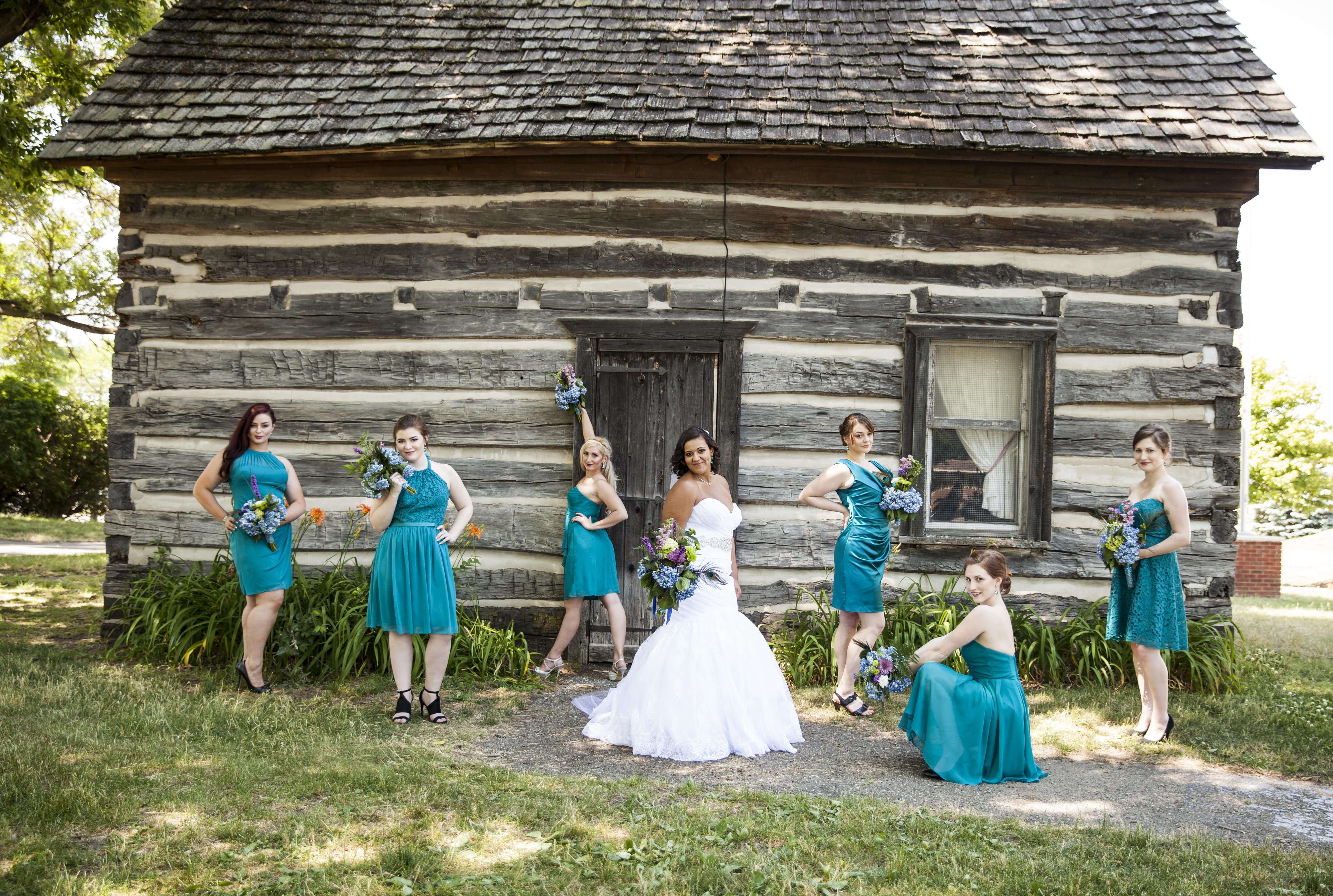 the bride and bride's maids posing in front of an old cabin