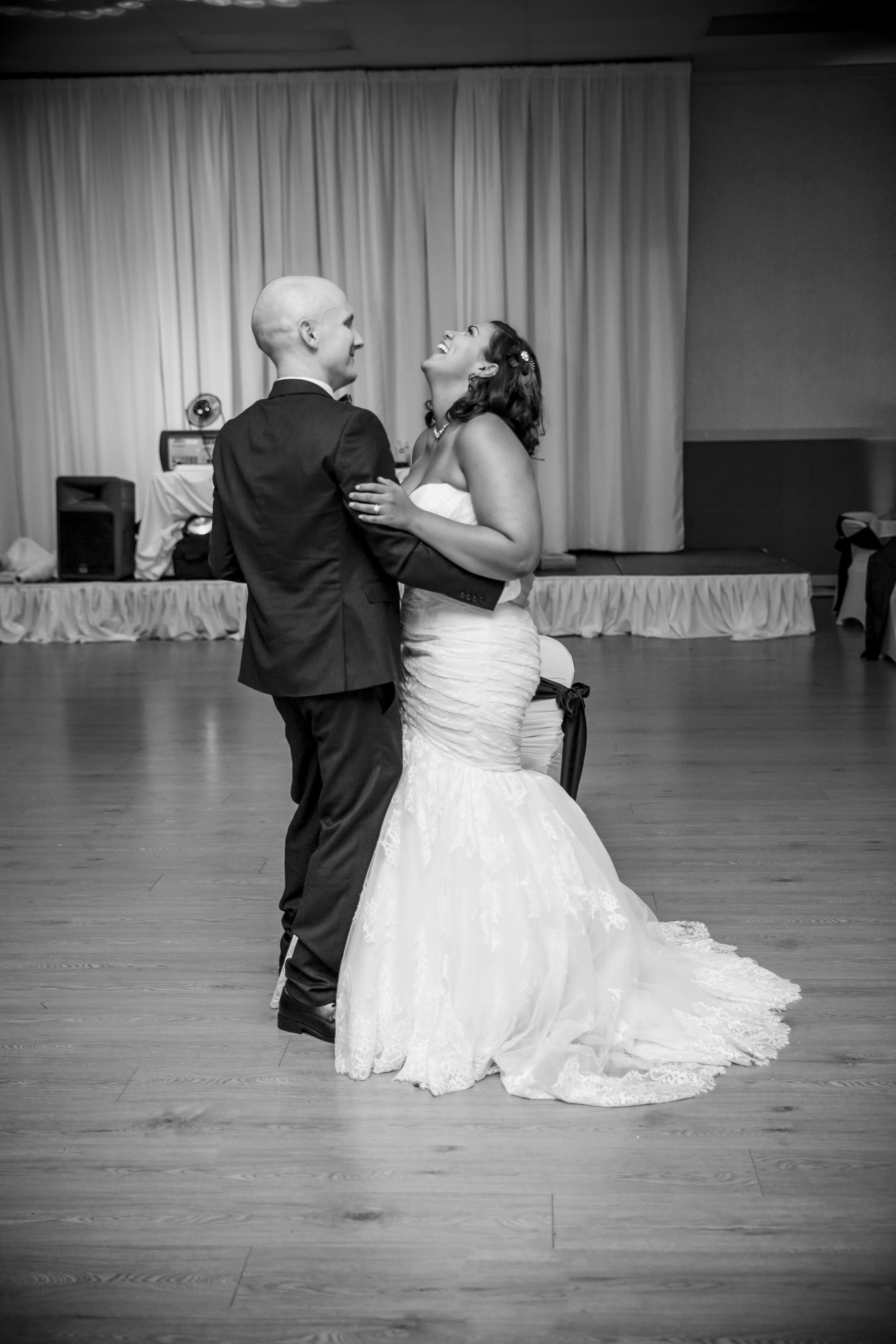 black and white photo of the bride and groom's first dance with the bride laughing