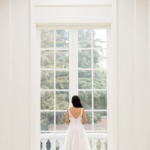Back of Beautiful lace and chiffon wedding dress, Maryam infront of a big window