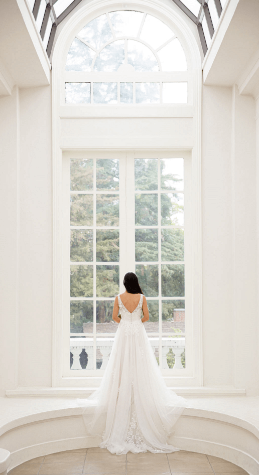 Back of Beautiful lace and chiffon wedding dress, Maryam infront of a big window